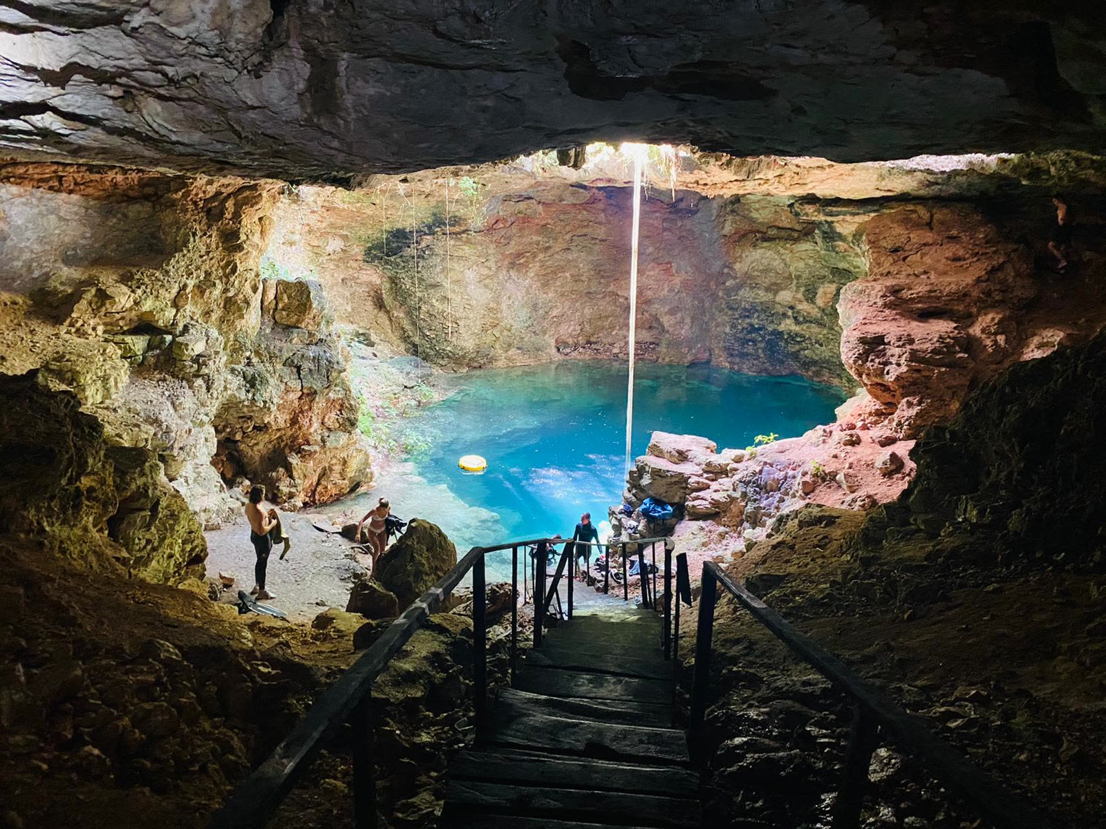 Cenote Ucil — a sunlit cavern pool in the Yucatán, Mexico, with wooden steps down to clear blue water
